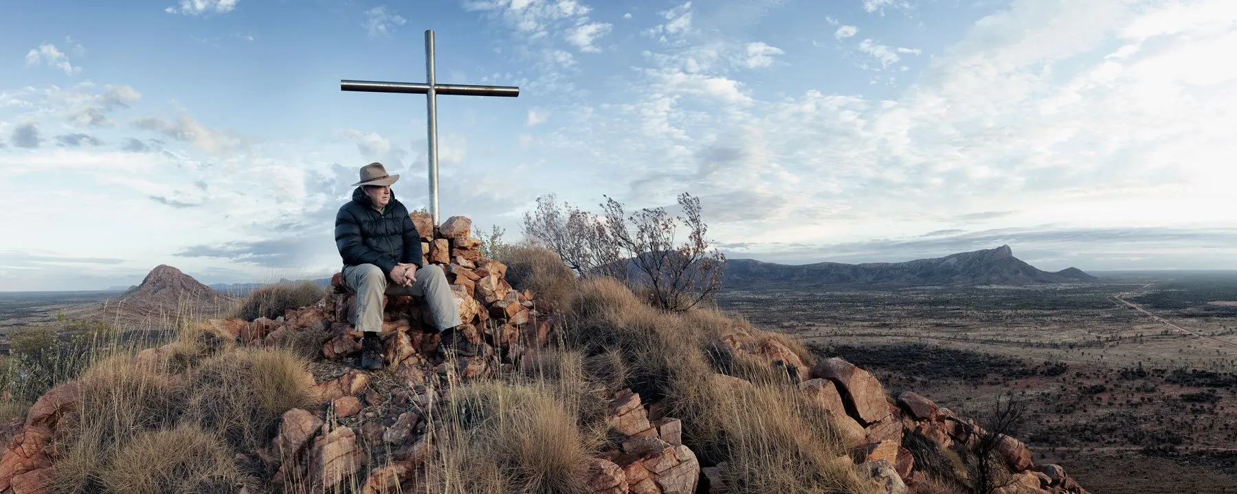 Ken Duncan seated beside a cross on Memory Mountain
